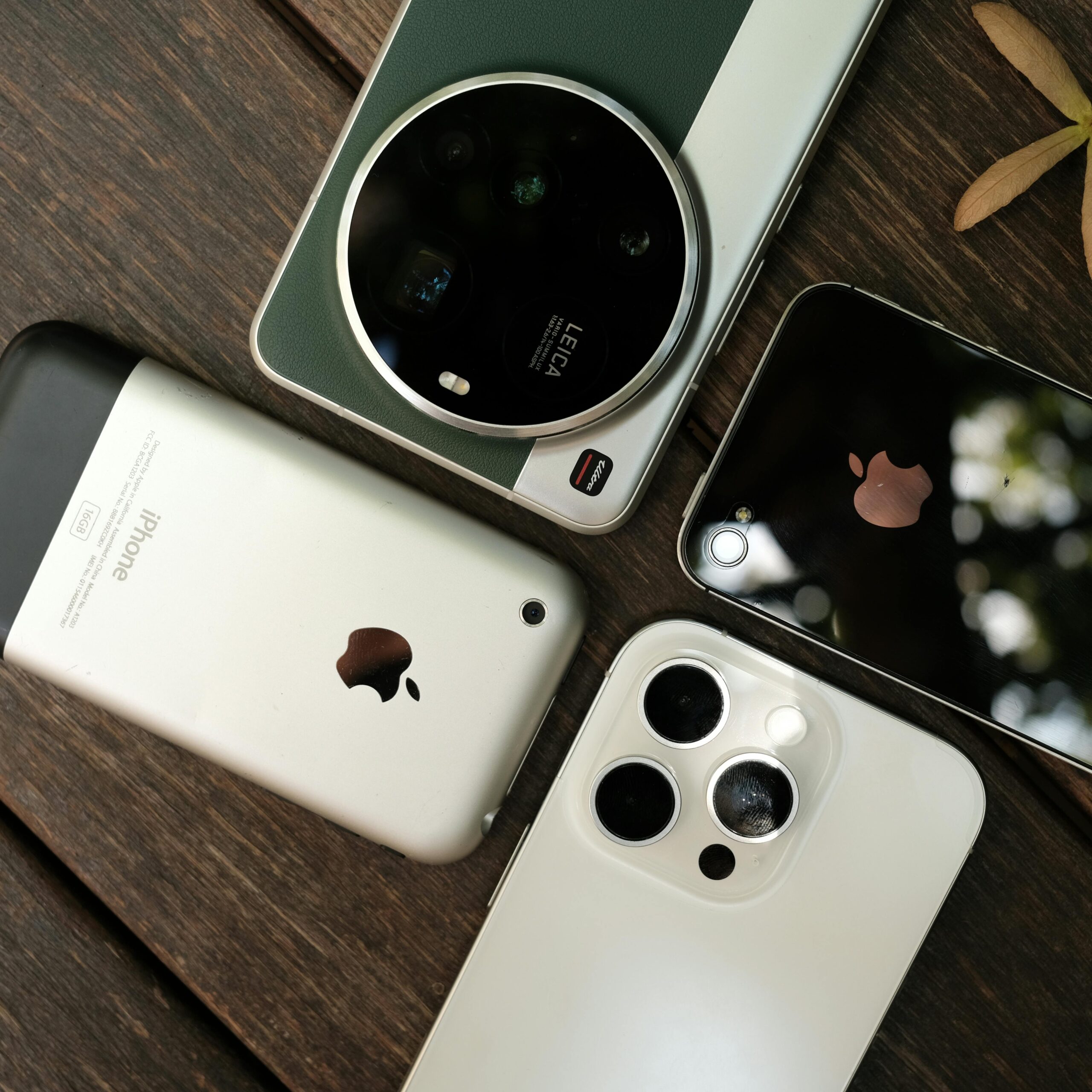 Aerial shot of multiple smartphone models on wooden table, showcasing camera designs.